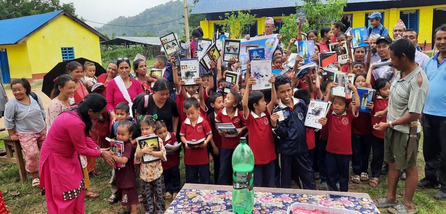 School kids happily getting learning materials from a social trekking organizer in Nepal.