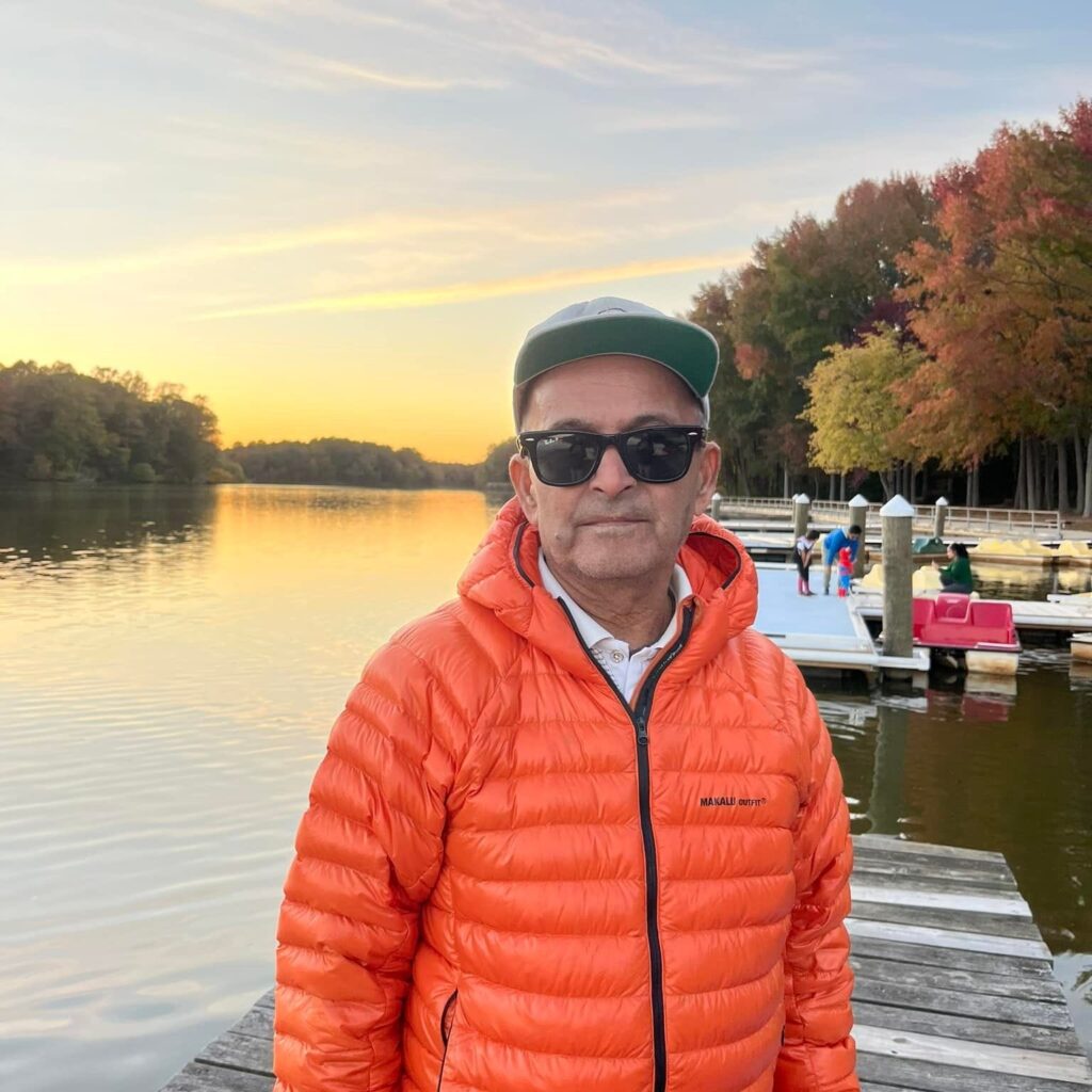 Person in orange jacket by lake.