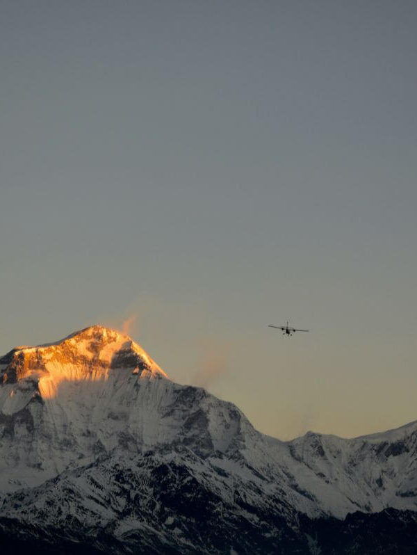 Dhaulagiri glowing gold at sunrise with a small plane flying past, seen from Poon Hill on the Ghorepani Poon Hill Trek, Nepal